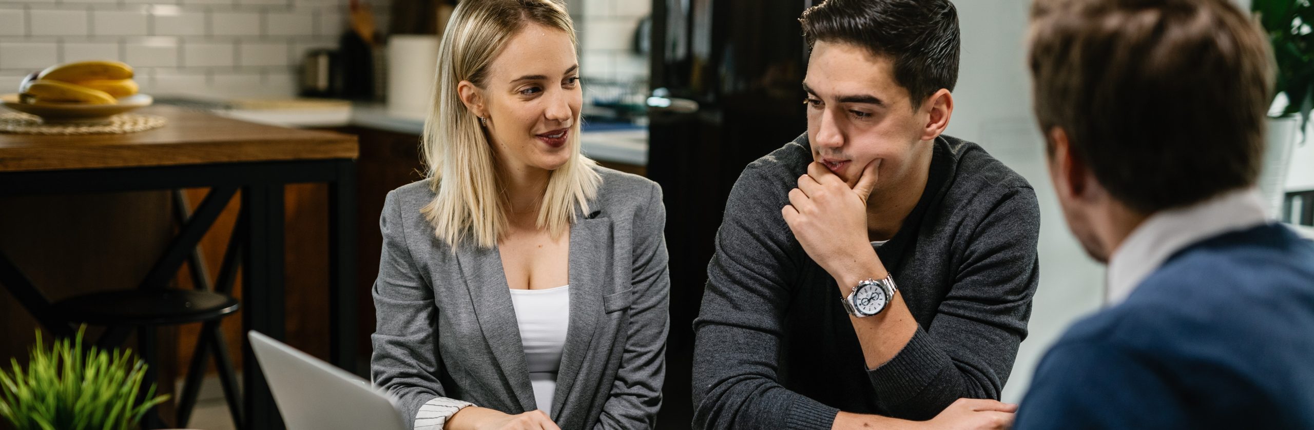 2_young-couple-talking-about-blueprints-while-having-meeting-with-investment-agent-using-computer